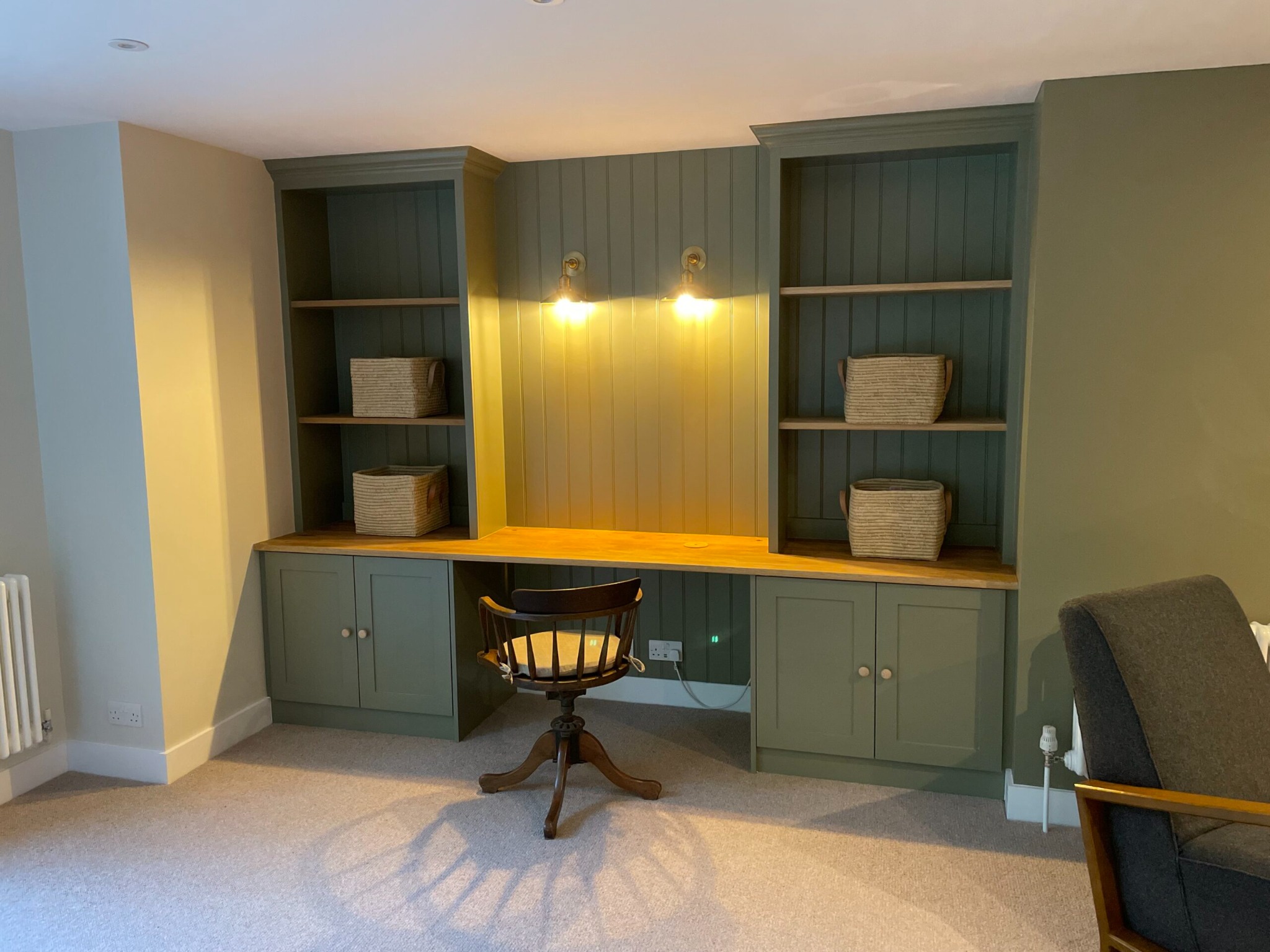 Bespoke green home office desk with shelves and wall lighting