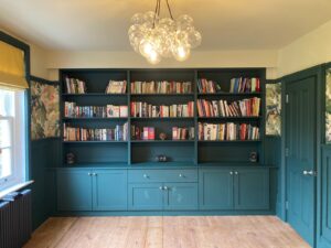 Built in bookcase with teal cabinetry and shelving in home library